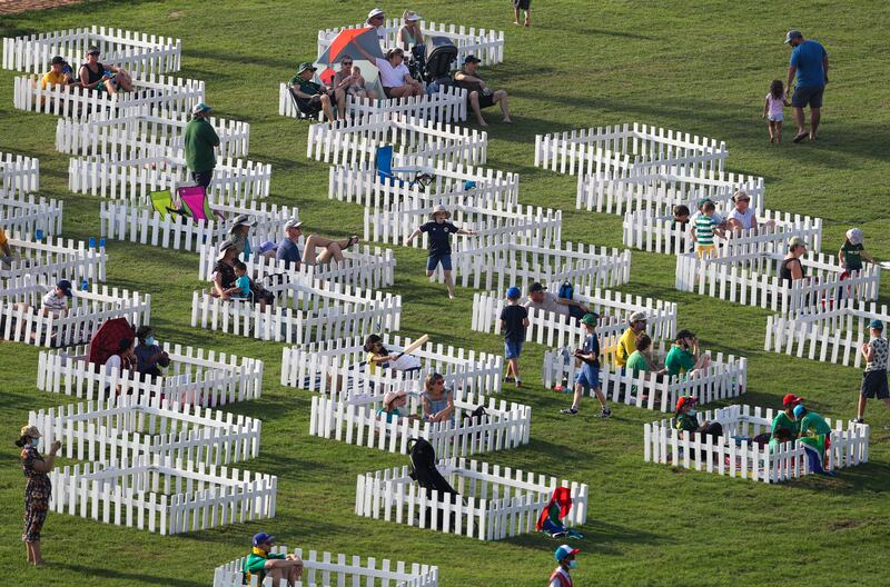 Spectators watch the opening match of the T20 World Cup from special fenced areas on the grass banks of Zayed Cricket Stadium. AP