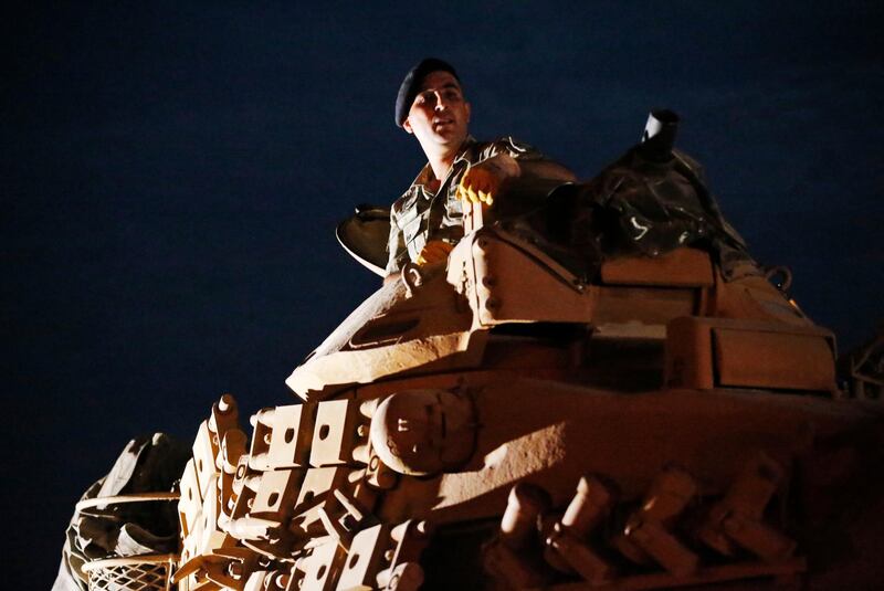 A Turkish army officer sits atop this tank as it moves to its new position on the Turkish side of the border between Turkey and Syria, in Sanliurfa province, southeastern Turkey. AP Photo