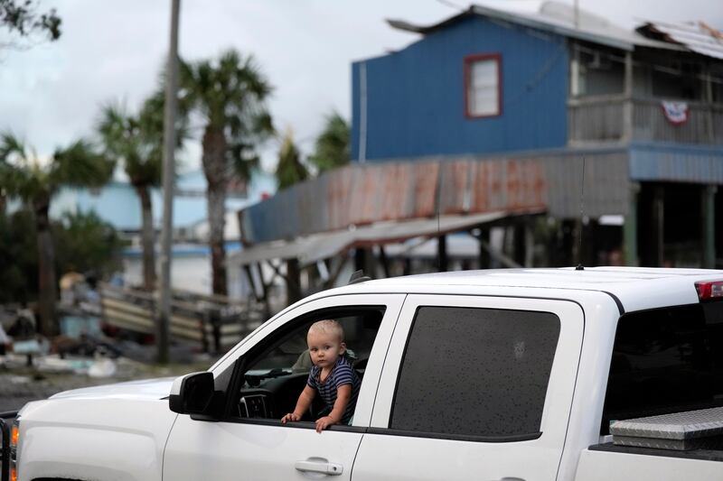 A child looks out the window of a car picking its way through Horseshoe Beach, surveying storm damage. AP