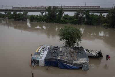 A metro train moves on a bridge as a house is submerged in flood waters in New Delhi, India. Reuters 