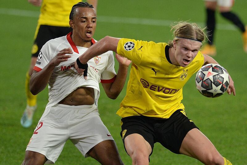 Dortmund's Norwegian forward Erling Braut Haaland (R) challenges Sevilla's French defender Jules Kounde during the UEFA Champions League round of 16 first leg football match between Sevilla FC and Borussia Dortmund at the Ramon Sanchez Pizjuan stadium in Seville on February 17, 2021. / AFP / CRISTINA QUICLER                    
