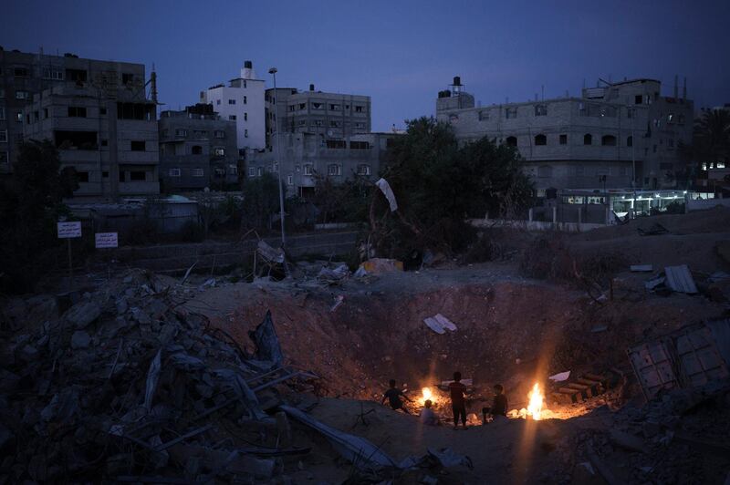 Children gather around a fire next to their destroyed home more than a week after a ceasefire ended the 11-day war between Israel and Gaza's Hamas rulers, in Beit Lahia, northern Gaza Strip. AP Photo