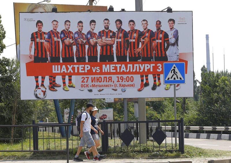 People walk by under a poster advertising Shakhtar Donetsk in downtown Donetsk, Ukraine, on July 23, 2014. The club have moved their operations to the west of the countries with violence still prevalent in the east. Robert Ghement / EPA