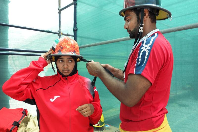 Sgt Hasna Juma Al Shamsi gets help preparing for her first firefighter challenge from fellow UAE member, Hassan Al Babooshi. 