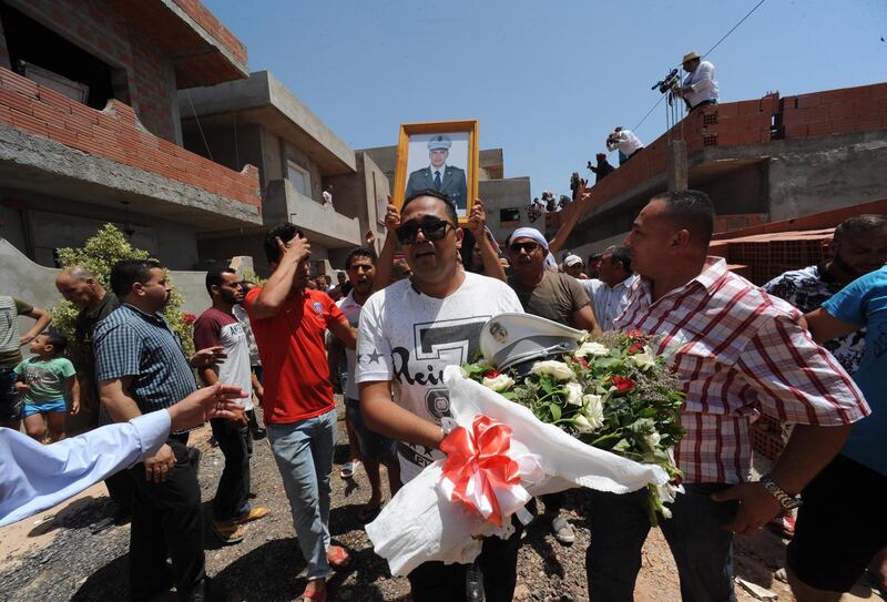 A man carries flowers and the police hat of Sgt Arbi Guizani, as others carry his picture and body during his funeral on July 9, 2018, in Ettadhamen, a suburb of the capital Tunis. EPA