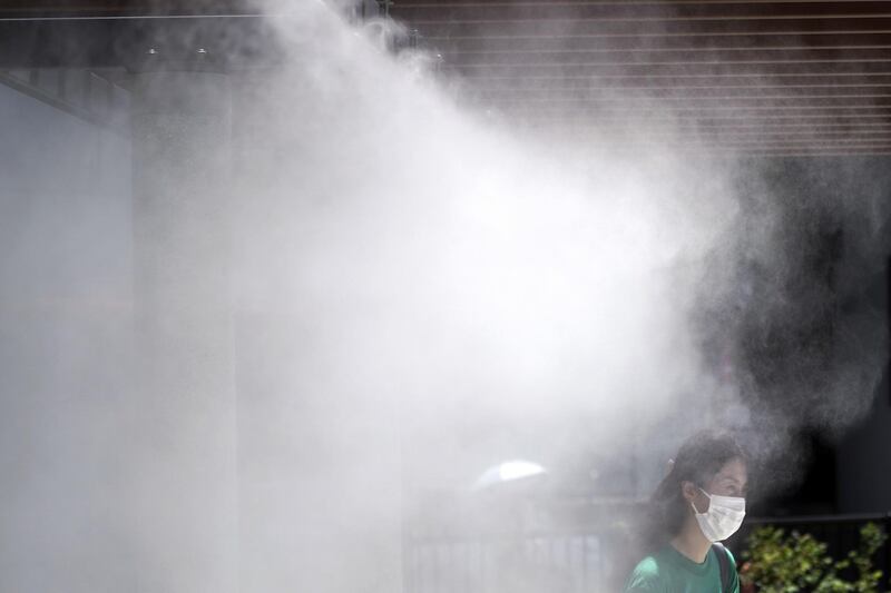 A woman cools down under a cooling mist spot at a street in Tokyo, Japan. AP Photo