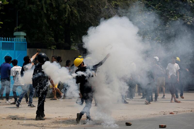 Protesters hurl back tear gas canisters towards police in Mandalay. AP Photo