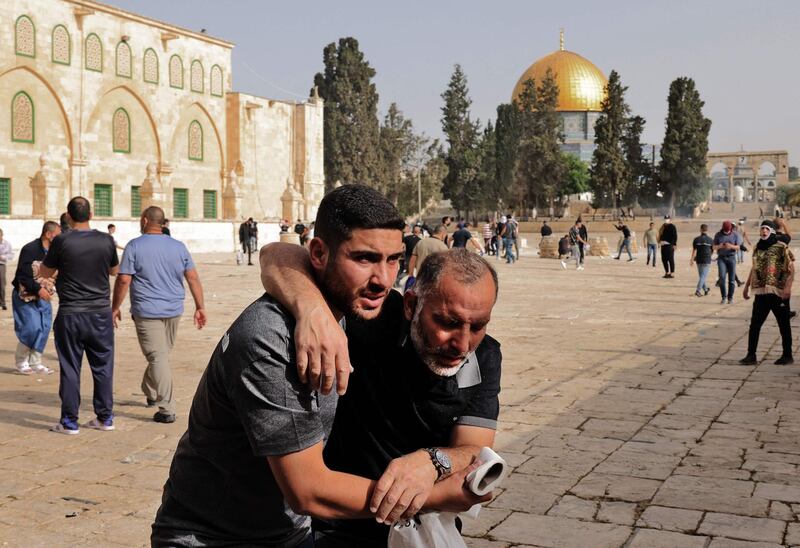 A Palestinian man helps a wounded fellow protester amid clashes with Israeli security forces at Jerusalem's Al Aqsa Mosque compound. AFP