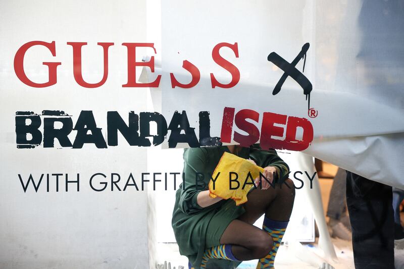Employees at the London Guess store remove lettering from a window display that included Banksy's Flower Thrower artwork. Reuters / Henry Nicholls