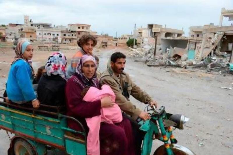 A Syrian family, on a three wheeled motorcycle, leave the northern Syrian town of Taftanaz, in the Idlib province, following heavy shelling by government forces. Philippe Desmazes / AFP