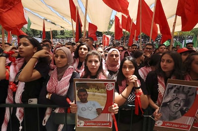 Palestinian students supporting the Popular Front for the Liberation of Palestine (PFLP) lift flags of the movement and placards at Birzeit University on the outskirts of Ramallah in the occupied West Bank, on May 17, 2022. The placard on the right depicts the late founder of the PFLP George Habash. AFP