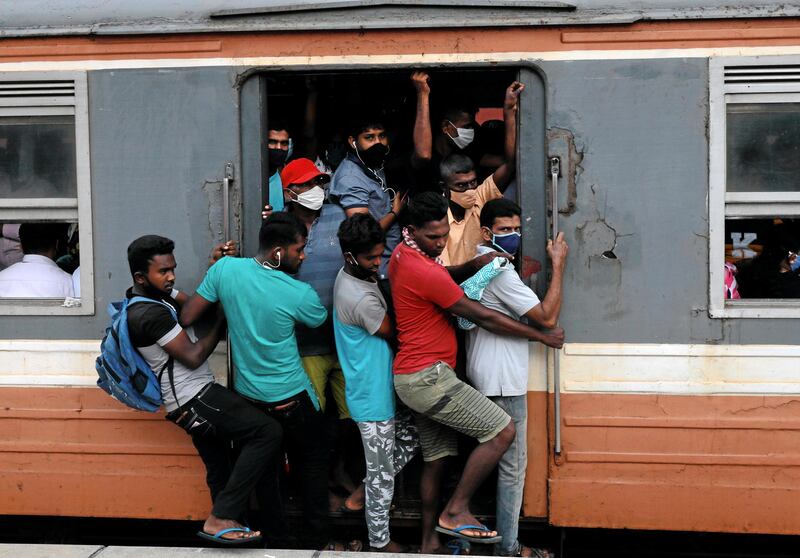 Passengers hang on to a train during the daily commute in Colombo, Sri Lanka. Reuters