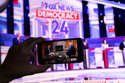 A viewer watches the first Republican presidential debate live on Fox News as well as Donald Trump's interview with Tucker Carlson on the X app. EPA