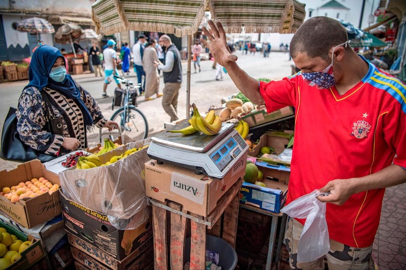 A vendor, wearing a protective mask, weighs bananas at the central market in the Moroccan capital Rabat. AFP