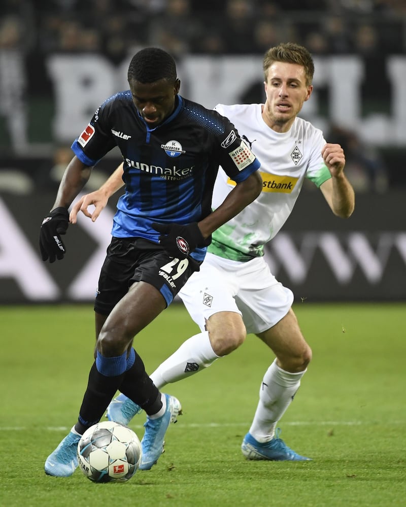 Paderborn's Jamilu Collins and Moenchengladbach's German forward Patrick Herrmann (R) vie for the ball during the German first division Bundesliga football match Borussia Moenchengladbach v SC Paderborn, on December 18, 2019 in Moenchengladbach. (Photo by INA FASSBENDER / AFP) / DFL REGULATIONS PROHIBIT ANY USE OF PHOTOGRAPHS AS IMAGE SEQUENCES AND/OR QUASI-VIDEO