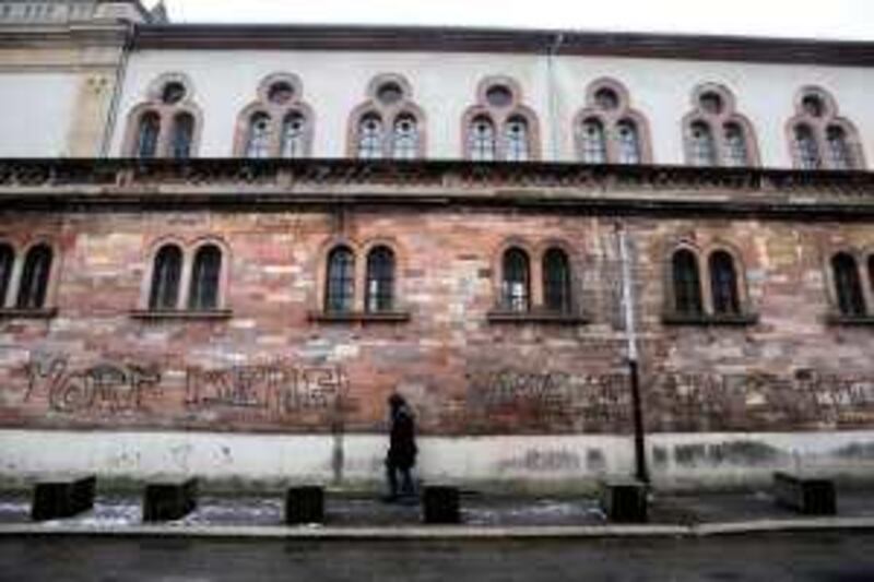 A man walks past the walls of a synagogue on January 14, 2009 in Mulhouse, eastern France, tagged overnight with an inscription reading in French "Israel to the death, long life to Palestine". France, home to Europe's biggest Muslim and Jewish communities, has been hit by 55 anti-Semitic attacks since the start of Israel's Gaza offensive, a Jewish student group said.   AFP PHOTO  SEBASTIEN BOZON *** Local Caption ***  086348-01-08.jpg