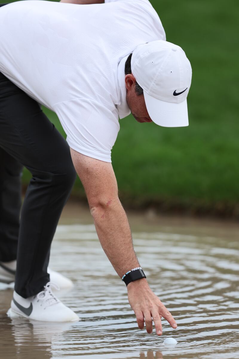 McIlroy collects his ball from a pond during the first round. EPA
