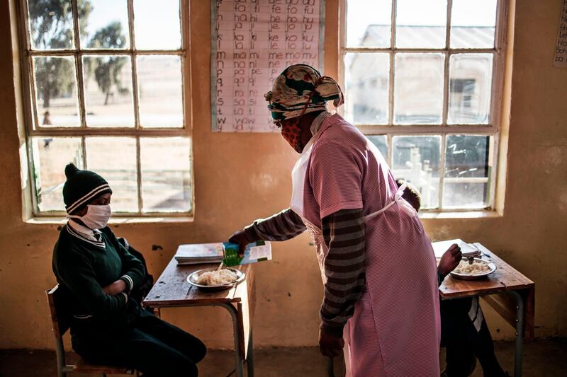 Grade 7 pupils of the Sitoromo Junior Secondary School in Sterkspruit, South Africa, sit in their classroom as a cook pours milk into a steaming dish of maize porridge. The school reopened only for Grade 7 pupils after being shut for two weeks because of a Covid-19 case found among its staff.  AFP