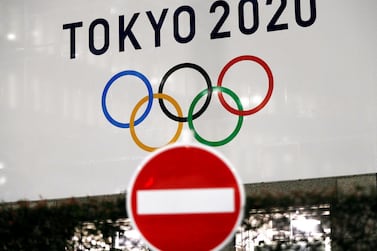 A banner for the upcoming Tokyo 2020 Olympics is seen behind a traffic sign, following an outbreak of the coronavirus disease (COVID-19), in Tokyo, Japan, March 23, 2020. REUTERS/Issei Kato
