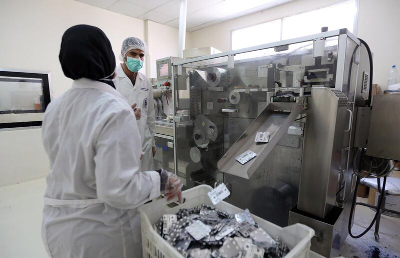 A laboratory technician stands next to drug-making machine at the Syrian Tamico Pharmaceutical Factory in Damascus. The factory is producing Azithromycin tablets, which are used with hydroxychloroquine as one of the treatments for patients with Covid-19. Youssef Badawi / EPA