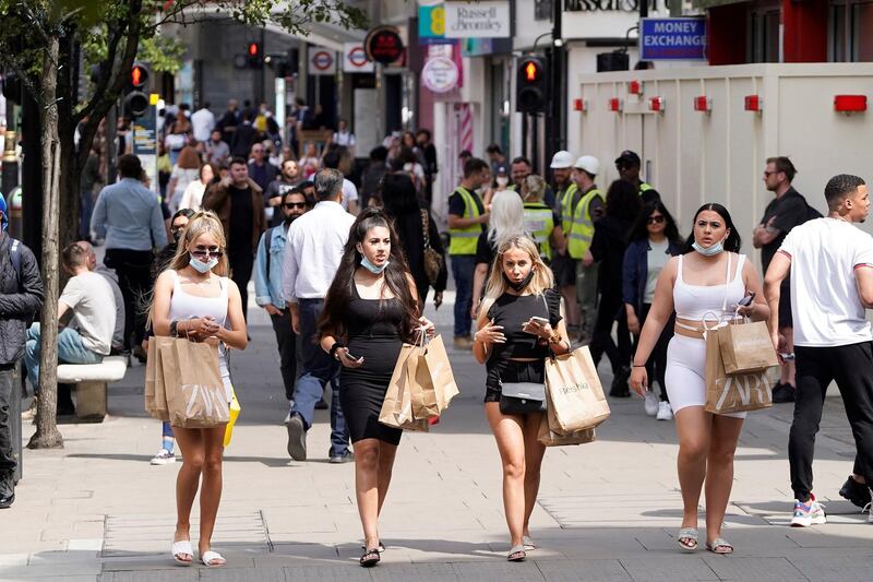 Shoppers wearing face coverings due to Covid-19, but pulled down under their chin, walk along Oxford Street in central London on June 7, 2021. The Delta variant of the coronavirus, first discovered in India, is estimated to be 40 percent more transmissible than the Alpha variant that caused the last wave of infections in the UK, Britain's health minister said Sunday. / AFP / Niklas HALLE'N

