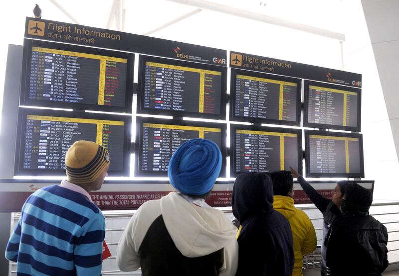 NEW DELHI, INDIA - DECEMBER 22: The passengers looking at flight schedule display at T-3 terminal Indira Gandhi International Airport in the cold and foggy morning on December 22, 2014 in New Delhi, India.  Dense fog reduced visibility to 50 metres. Due to poor visibility, 16 flights were delayed. It was the coldest December 22 in the national capital in the past five years with minimum temperature recorded at 4.2 degrees Celsius. (Photo by Sushil Kumar/Hindustan Times via Getty Images)