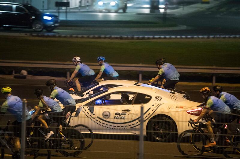 Early participants ride along with a Dubai Police patrol car.