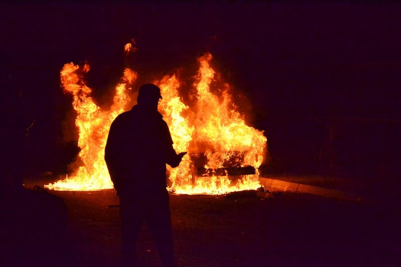 A man passes in front a car that was set on fire during a protest against strict lockdown measures in Tripoli. AP