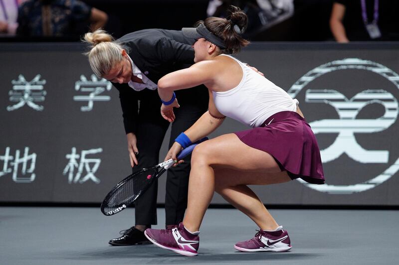 The umpire looks as Bianca Andreescu struggles to stand up after injuring her leg. AP