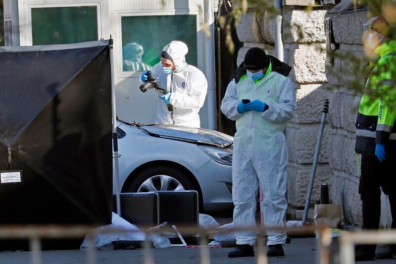 Police collect evidence at the scene after a car crashed into the gates of the Russian embassy in Bucharest, Romania. EPA