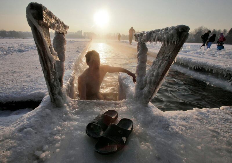 A Russian man climbs out from an ice hole after swimming in a lake on the outskirts of St. Petersburg, Russia, Sunday, Feb. 5, 2012. The temperature in St. Petersburg hit -23 Celsius (-9.4 Fahrenheit).  (AP Photo/Dmitry Lovetsky) *** Local Caption ***  Russia Europe Weather.JPEG-02a69.jpg