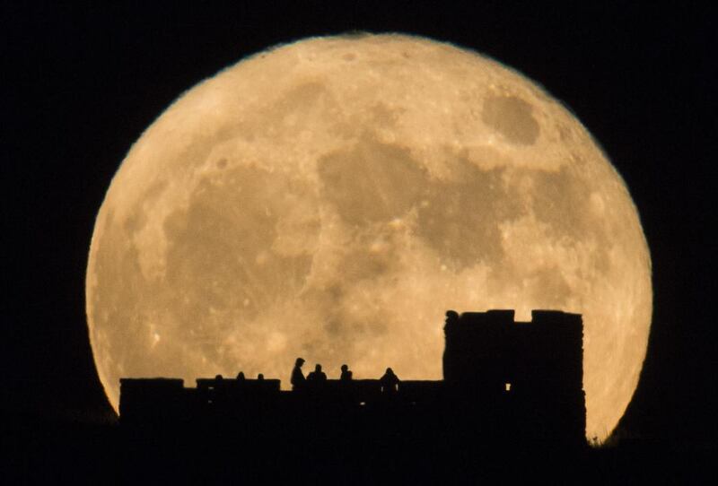 People watch the moon rise behind Coronado Heights near Lindsborg, Kansas. The brightest moon in almost 69 years is lighting up the sky in a treat for star watchers around the globe. Travis Heying / The Wichita Eagle via AP