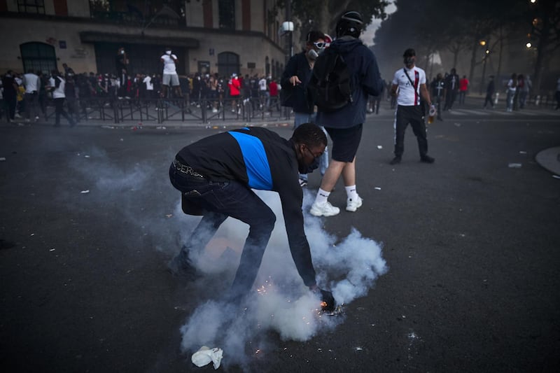 A Paris Saint-Germain fan picks up a tear gas canister. Getty