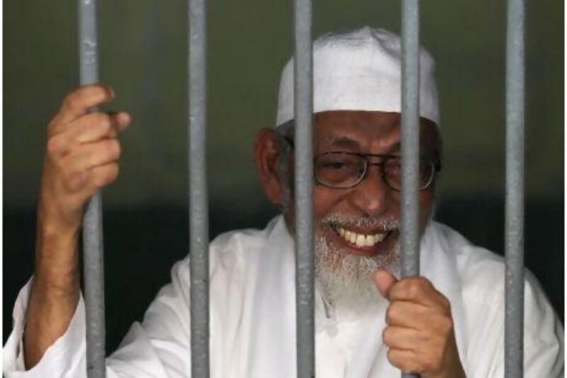 Islamic cleric Abu Bakar Bashir smiles as he talks to reporters from his cell before his trial in Jakarta.