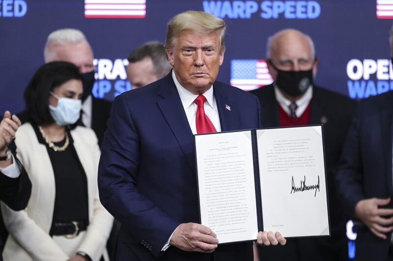U.S. President Donald Trump holds a signed executive order during an Operation Warp Speed vaccine summit at the White House in Washington, D.C., U.S., on Tuesday, Dec. 8, 2020. Trump celebrated the development of coronavirus vaccines at a White House summit on Tuesday and vowed to use executive powers if necessary to acquire sufficient doses, as the number of U.S. cases surpassed 15 million. Photographer: Oliver Contreras/SIPA USA/Bloomberg