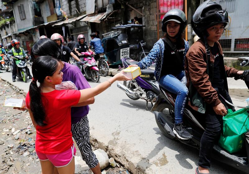 A Filipino motorcycle rider woman hands over a box of goods. EPA