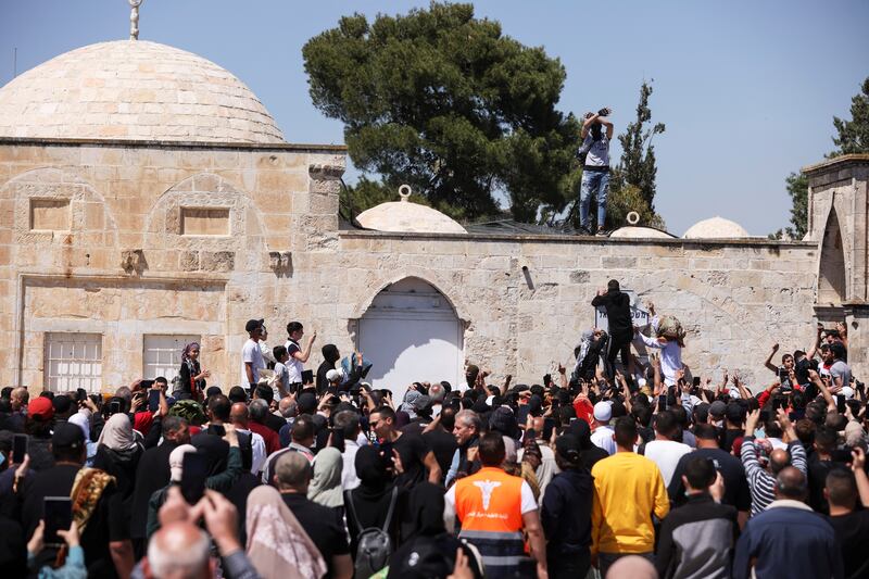 A Palestinian man removes a police sign from a wall at Al Aqsa Mosque compound after Israeli security forces used force against worshippers gathered for Ramadan prayers. Reuters