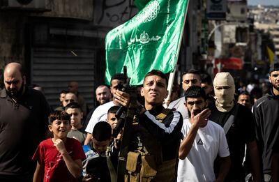 A Hamas flag flies as a man fires into the air at the funeral of men killed in an Israeli raid on Jenin refugee camp in November 2023. AFP