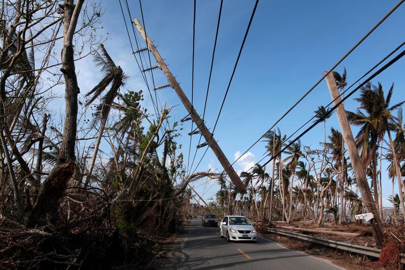 FILE PHOTO: Cars drive under a partially collapsed utility pole, after the island was hit by Hurricane Maria in September, in Naguabo, Puerto Rico October 20, 2017.   REUTERS/Alvin Baez/File Photo