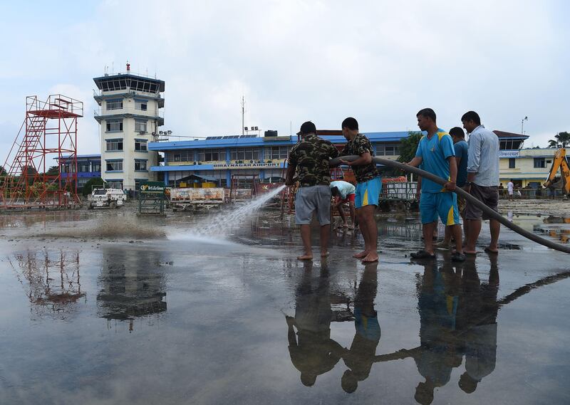 Members of the Nepali Army help clean mud left from floods which hit parts of Biratnagar's domestic airport, some 240km from Nepal's capital Kathmandu, on August 16, 2017. At least 221 people have died and more than 1.5 million have been displaced by monsoon flooding across India, Nepal and Bangladesh, officials said, as rescuers scoured submerged villages for the missing. PRAKASH MATHEMA / AFP