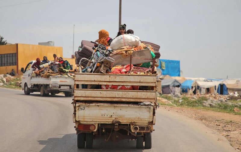 Syrian families, riding in the back of trucks loaded with their belongings, flee from reported regime shelling on Hama and Idlib provinces on May 1, 2019. Bombardment by the regime and its Russian ally on northwestern Syria has displaced nearly 140,000 people since February, the UN said today.  / AFP / Aaref WATAD
