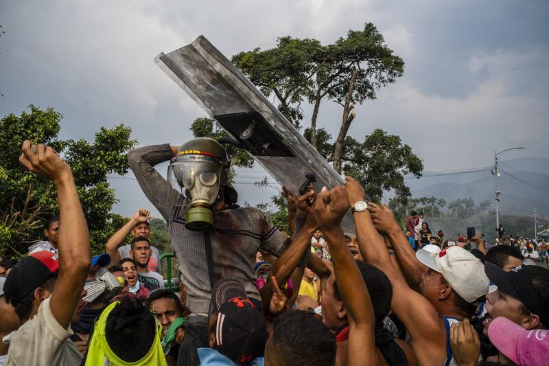 Demonstrators react after capturing a gas mask, a helmet and a shield from a Venezuelan soldier during clashes on the Simon Bolivar International Bridge near the border with Venezuela in Cucuta, Colombia. Bloomberg