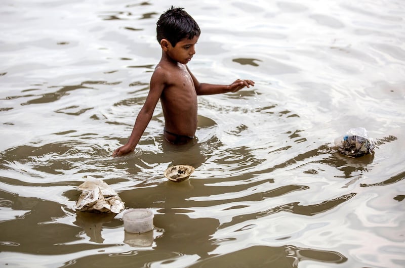 epa06087536 A boy takes a bath in the river Ganges as plastic bags and waste items float on water, in Calcutta, Eastern India, 14 June 2017. Top Indian environment court National Green Tribunal (NGT) banned the dumping of rubbish and waste with in the 500 meter towards a most polluted stretch of the Ganges river, a news reports said.  EPA/PIYAL ADHIKARY
