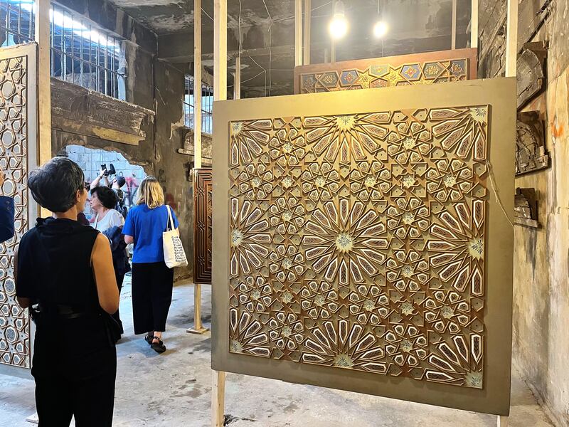 A  visitor admires a carved wood decorative panel made by the Tarazi family. 