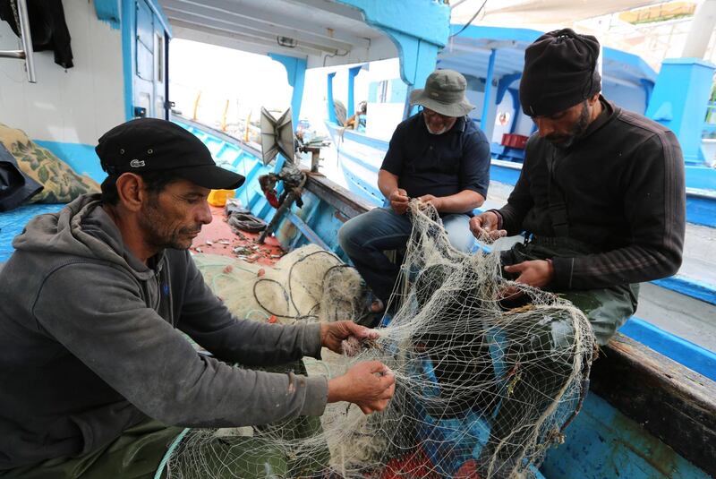 Tunisian fishermen prepare their nets inside a boat in the port of Zarzis in the southern coast of Tunisia on May 21, 2019. - Tunisian fishermen are finding themselves more and more involved in rescuing illegal boats leaving Libya for Italy, due to the difficulties of NGOs in the eastern Mediterranean and the disengagement of European military ships. Most of the fishermen have already brought back migrants - saving hundreds of lives over the years. (Photo by FATHI NASRI / AFP)
