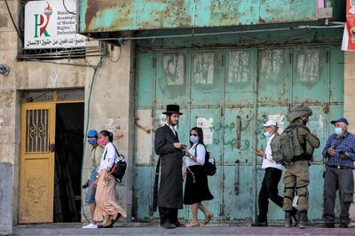 An Israeli soldier speaks with an old man while an Ultra-Orthodox Jewish man stands nearby in the city of Hebron in the occupied West Bank. AFP