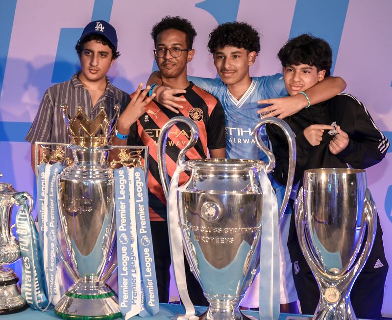 Manchester City fans pose with the club's trophies at the Louvre Abu Dhabi