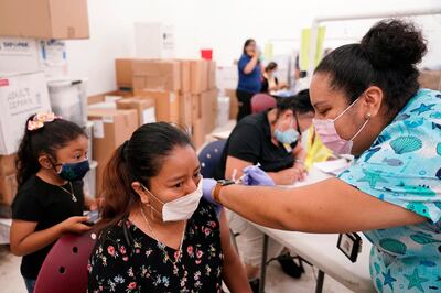 FILE - In this April 10, 2021, file photo, registered nurse Ashleigh Velasco, right, administers the Johnson & Johnson COVID-19 vaccine to Olga Perez at a clinic held by Healthcare Network, in Immokalee, Fla. With coronavirus shots now in the arms of nearly half of American adults, the parts of the U.S. that are excelling and those that are struggling with vaccinations are starting to look like the nationâ€™s political map: deeply divided between red and blue states. (AP Photo/Lynne Sladky, File)