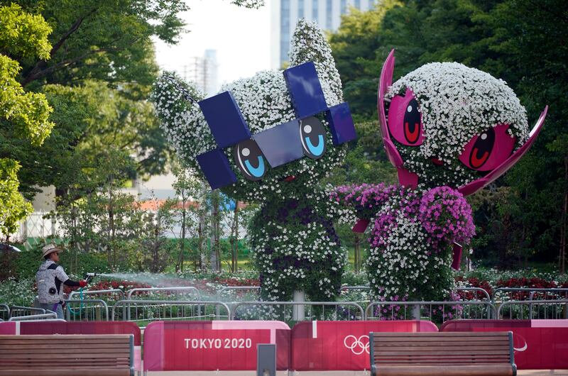 A gardener waters trees cut in the shape of the Tokyo 2020 Olympics mascots in Tokyo, Japan, July 22, 2021.