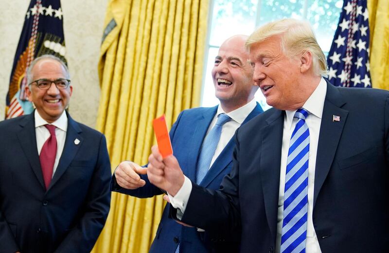 TOPSHOT - FIFA President Gianni Infantino (C) laughs are US President Donald Trump holds a red card during a meeting in the Oval Office of the White House in Washington, DC on August 28, 2018. Infantino offered Trump a set of yellow and red cards. - At left is US Soccer Federation President Carlos Cordeiro. (Photo by MANDEL NGAN / AFP)